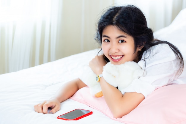 Cute teenage female joyful with smartphone on bed