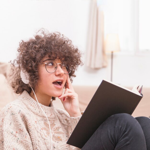 Cute teenager reading book and listening to music