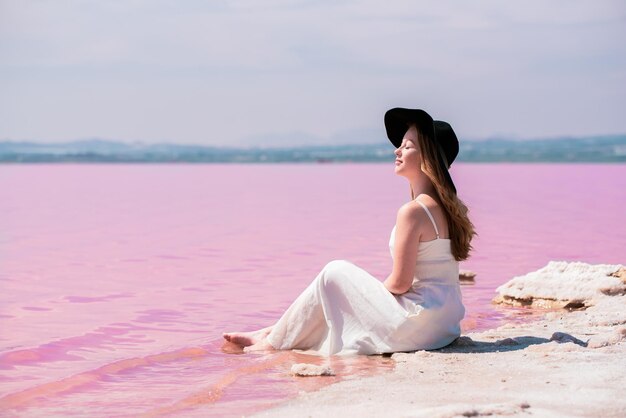 놀라운 핑크 호수에 앉아 흰 드레스를 입고 귀여운 십 대 여자