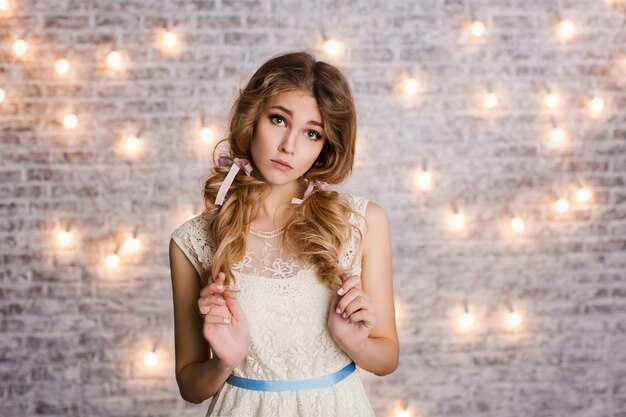 Cute tender slim girl with blond curly hair standing