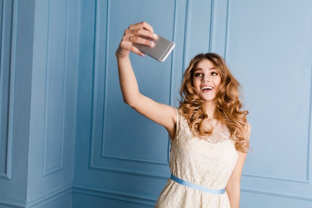 Cute tender slim girl with blond curly hair standing