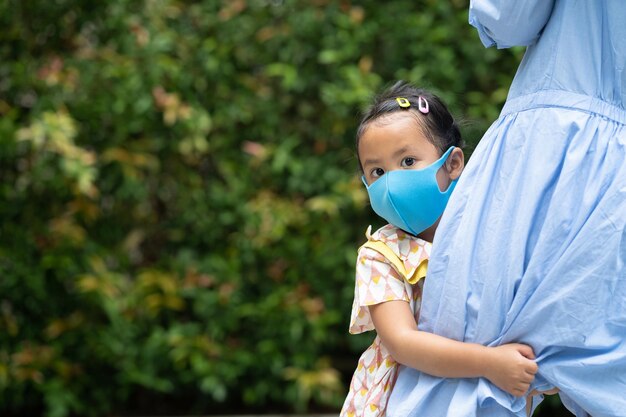 Foto gratuita carina ragazza tailandese con una maschera per il viso che abbraccia sua madre