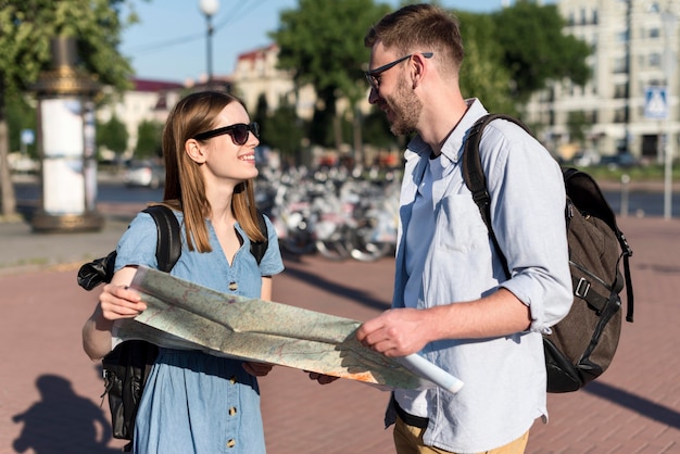 Free photo cute tourist couple holding map together