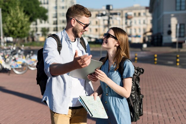 Cute tourist couple holding tablet and map