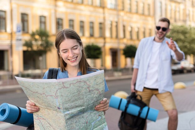 Cute tourist couple posing with map and backpack