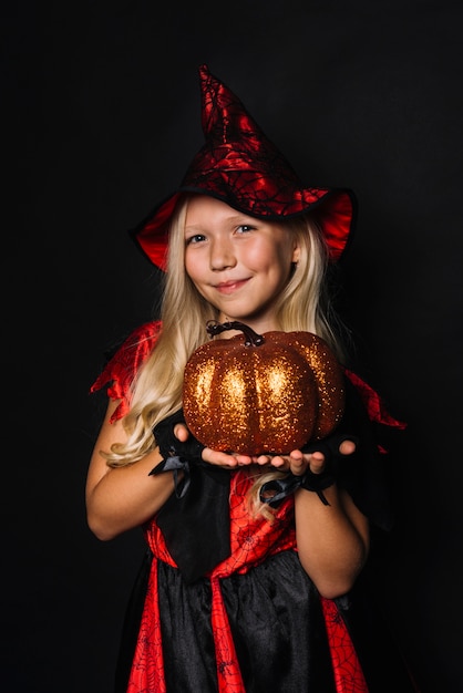 Cute witch showing pumpkin