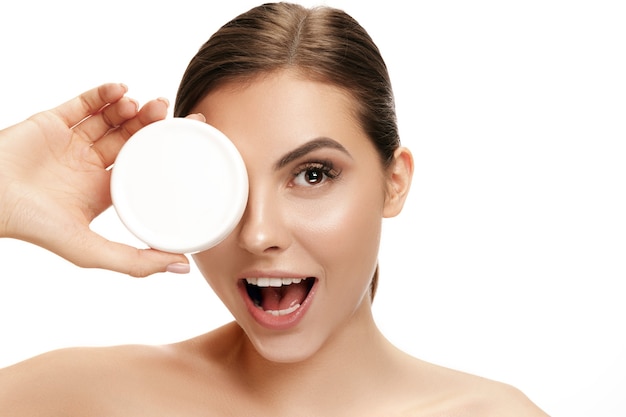 Free photo cute woman applying moisturizer cream on face at studio