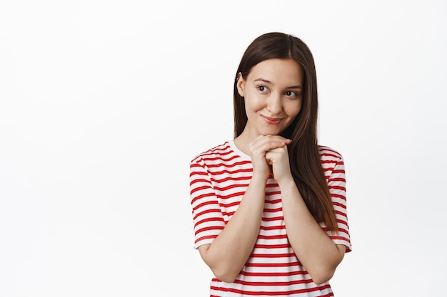 Cute woman contemplate smth adorable, looking aside with romantic, dreamy face expression, gazing admire something beautiful, standing against white background