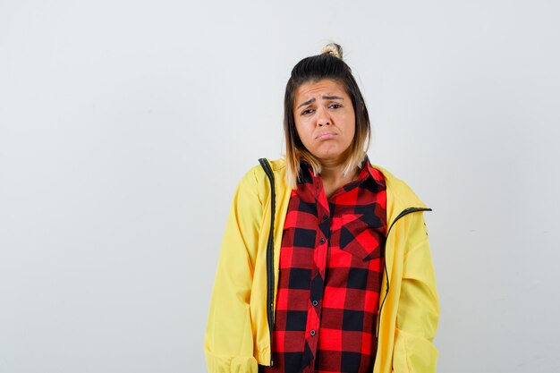 Cute woman curving lower lip in shirt, jacket and looking disappointed , front view.