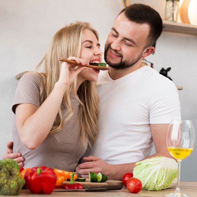Cute woman eating cucumber with her man