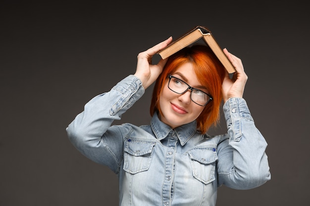 Cute woman hold book on head smiling