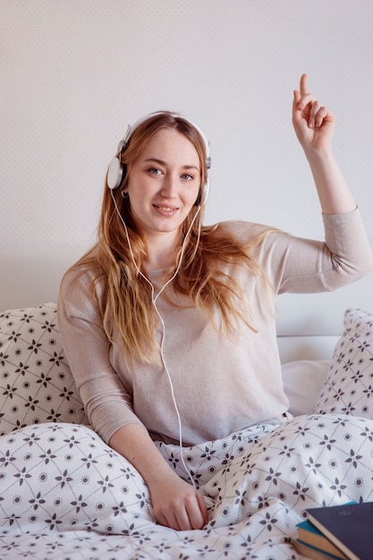 Free photo cute woman listening to music in bed