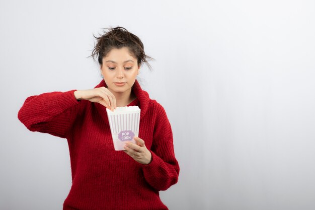 Cute woman looking into a bucket with popcorn.