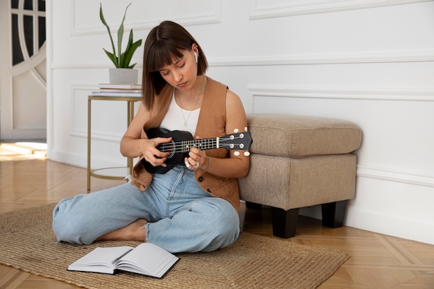 Милая женщина играет на гавайской гитаре дома