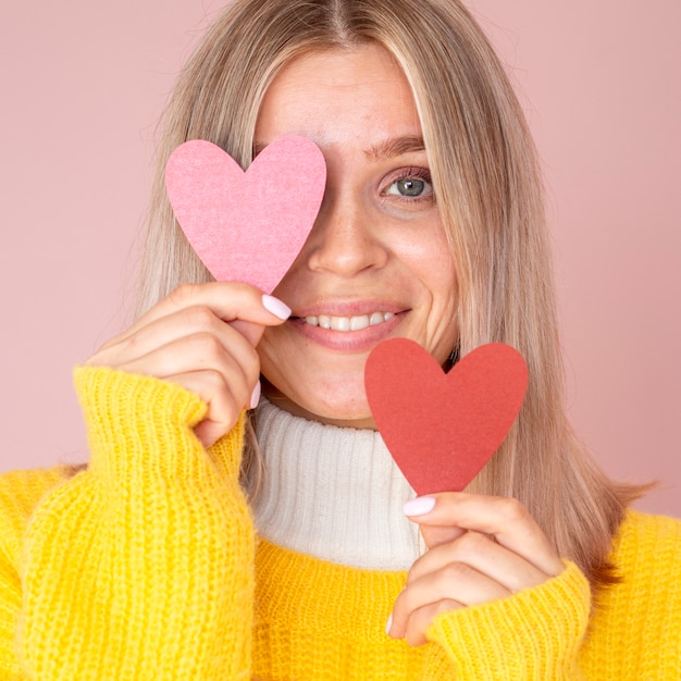 Foto gratuita donna sveglia che propone con i cuori di carta