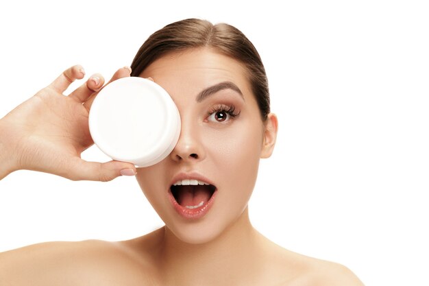 Cute woman preparing to start her day applying moisturizer cream on face