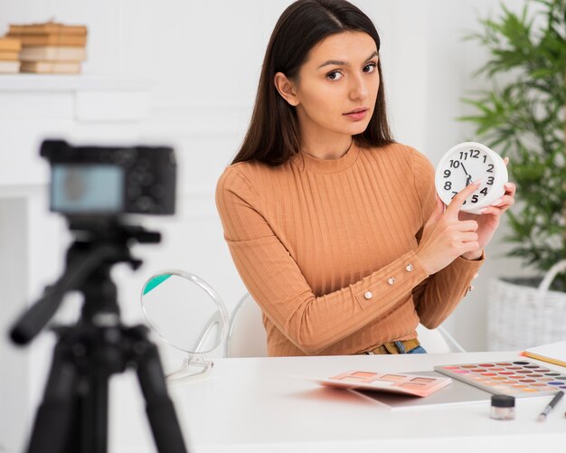 Cute woman presenting a clock