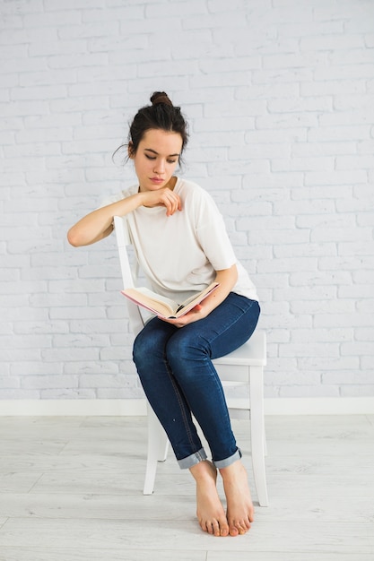 Cute woman reading book on chair