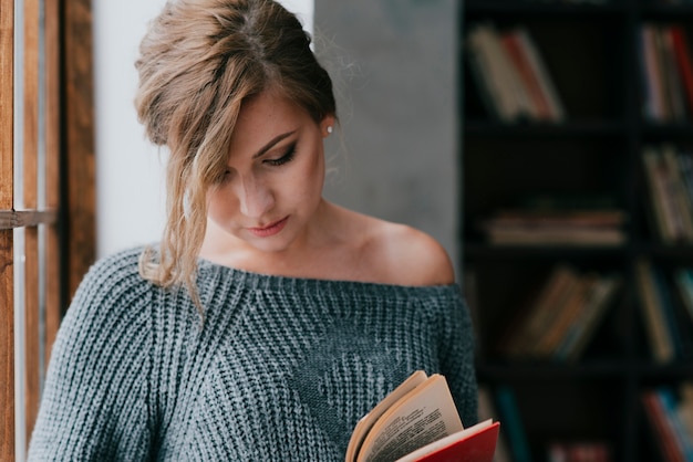 Foto gratuita donna sveglia che legge vicino alla finestra