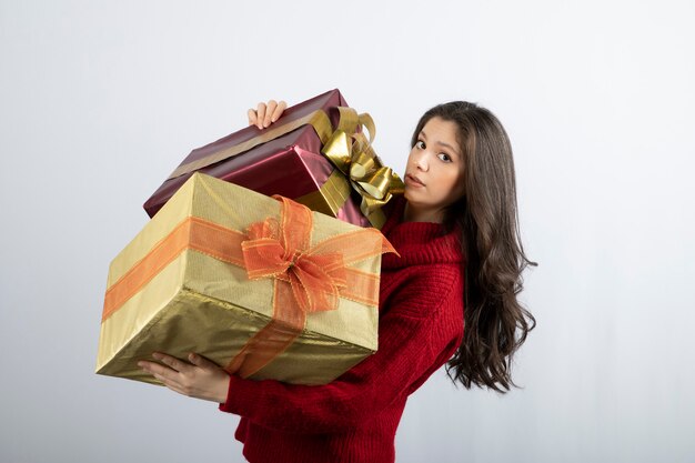 Free photo cute woman in red sweater holding christmas presents .