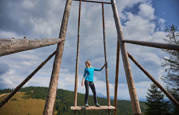 Cute woman resting on giant swing in the mountains