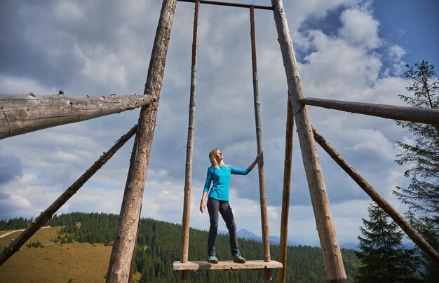 Cute woman resting on giant swing in the mountains