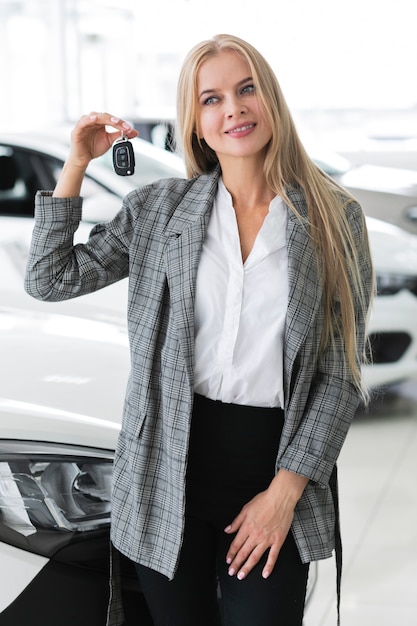 Foto gratuita donna sveglia che mostra alle chiavi dell'automobile e distogliere lo sguardo