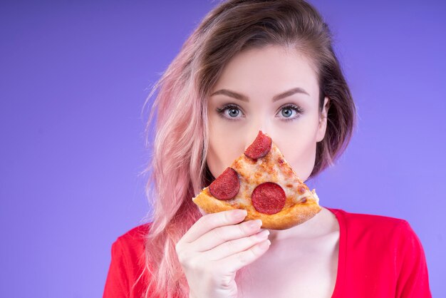 Cute woman showing a slice of pepperoni pizza