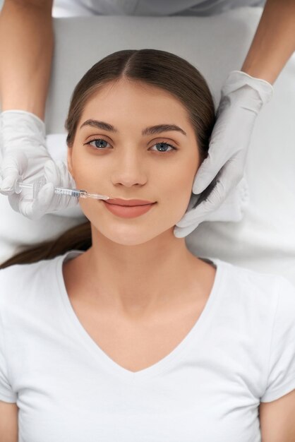 Cute woman in white shirt on procedure injection in lip