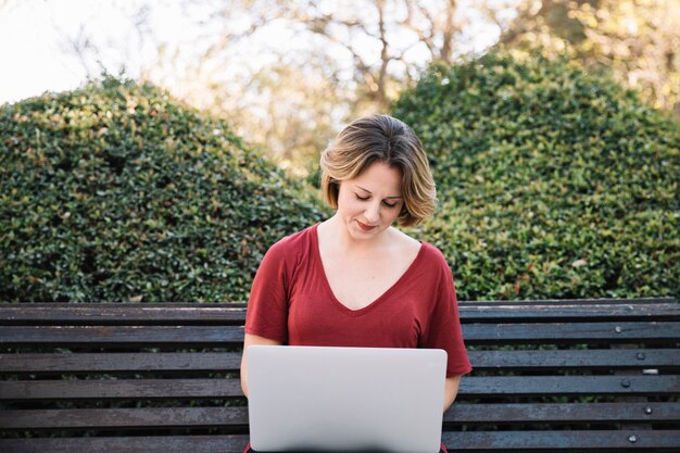 Cute woman with laptop in park