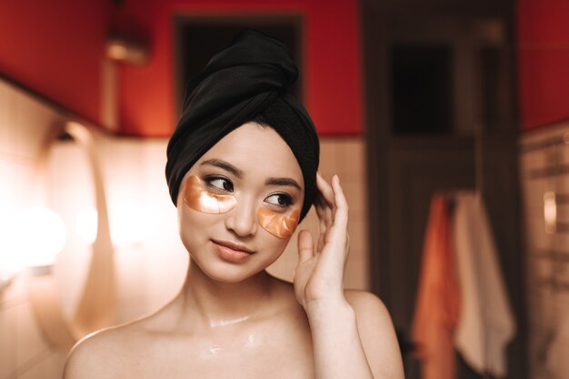 Cute woman with patches under eyes posing in bathroom