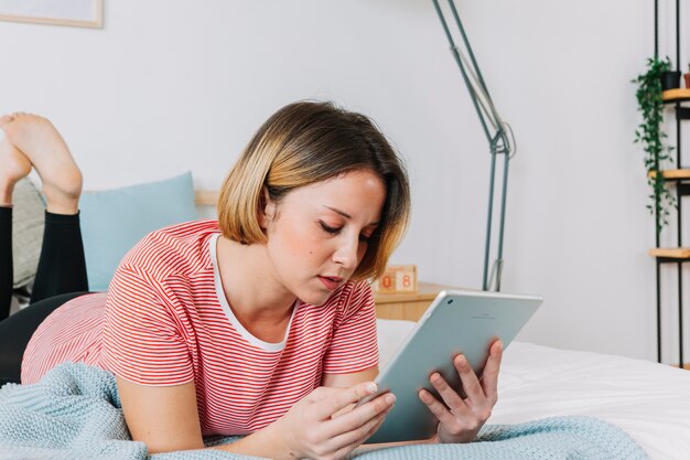 Cute woman with tablet on bed