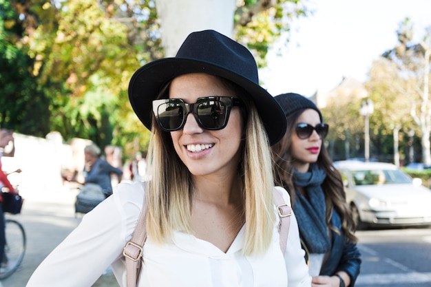 Cute women in hats walking on street