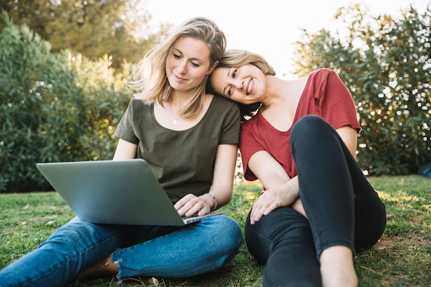 Donne sveglie che per mezzo del computer portatile su terra