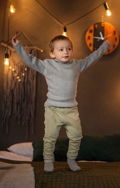 Free photo cute young boy jumping in bed