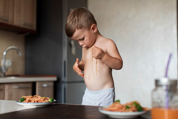 Cute young boy playing with spaghetti