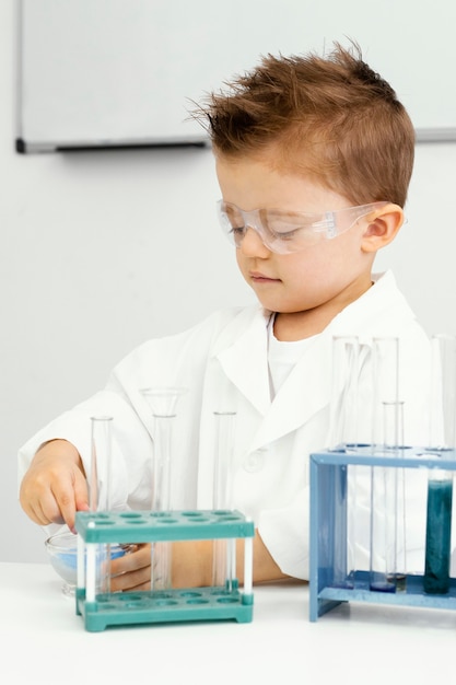 Бесплатное фото Милый мальчик-ученый делает эксперименты в лаборатории