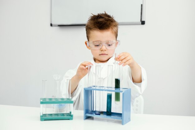 Cute young boy scientist doing experiments in the laboratory with test tubes