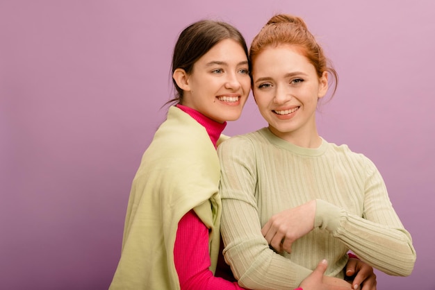 Cute giovani ragazze caucasiche bruna e rossa in abiti casual su sfondo viola concetto di stile di vita di emozioni sincere persone