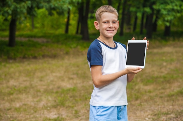 Cute young caucasian kid working with tablet in park