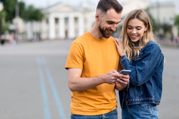 Free photo cute young couple looking at a phone