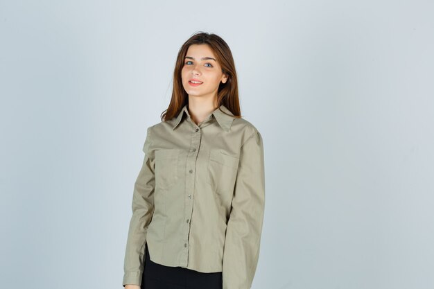 Cute young female looking at camera in shirt, skirt and looking cheerful. front view.