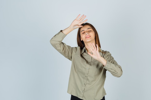 Cute young female showing refusal gesture, shutting eyes in shirt and looking ashamed. front view.