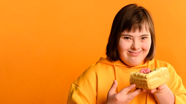 Симпатичная молодая девушка держит торт с копией пространства