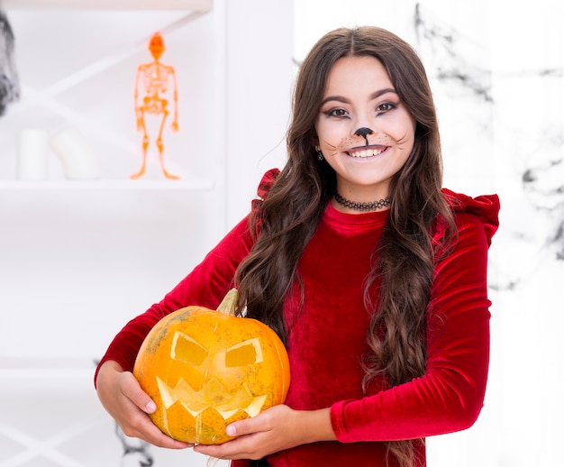 Free photo cute young girl holding evil halloween pumpkin