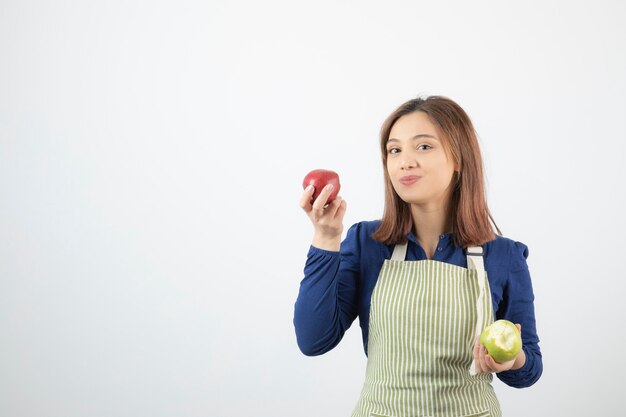 a cute young girl model in apron holding apples.