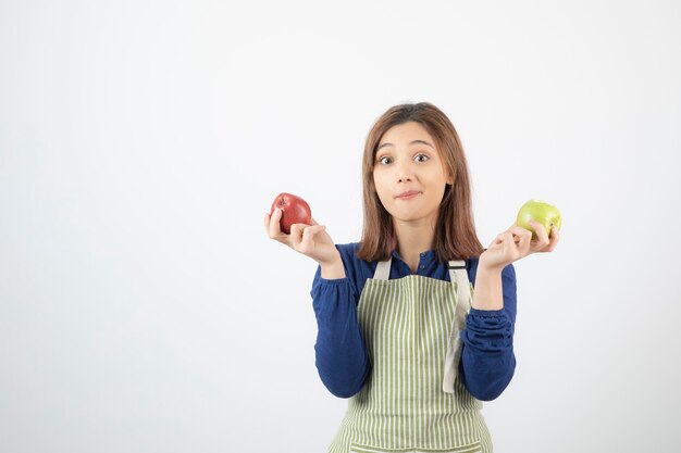 a cute young girl model in apron holding apples.