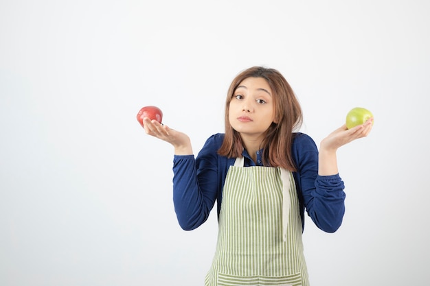 リンゴを保持しているエプロンのかわいい若い女の子モデル。