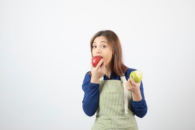 リンゴを保持しているエプロンのかわいい若い女の子モデル。