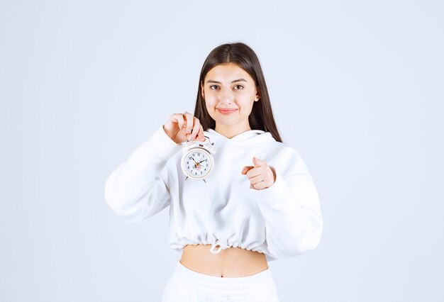 cute young girl model holding an alarm clock.